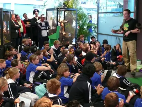 A keeper presenting to a room full of school students sitting on the floor